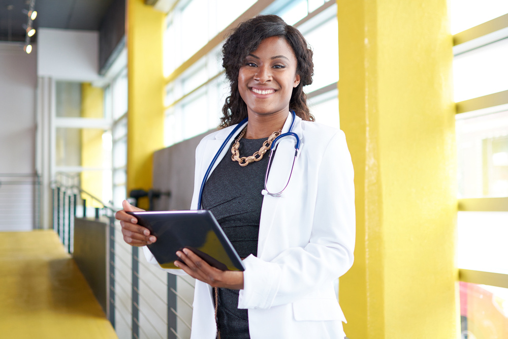 Portrait of a female doctor holding her patient chart on digital tablet in bright modern hospital